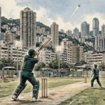 Cricket batsman in a dark green kit playing a lofted shot at a Hong Kong ground with tall buildings and floodlights behind him