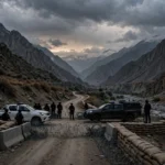 AI-generated editorial illustration of a police checkpoint with patrol vehicles and armed security personnel in a rugged mountain valley at dusk in North Waziristan, Pakistan