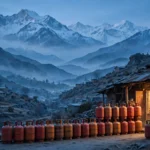 AI-generated editorial illustration of rows of red and orange LPG gas cylinders stacked outside a stone shop in a mountain town of northern Pakistan at dusk, with snow-capped peaks in the background.