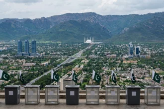 Empty ballot boxes with Pakistani flags overlooking the Islamabad skyline with the Faisal Mosque and Margalla Hills, as the ECP moves to schedule the capital's long-delayed local government elections