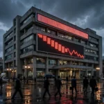 The Pakistan Stock Exchange building in Karachi at dusk with a glowing red descending chart on its facade as the KSE-100 sheds 1,965 points amid political uncertainty in October 2026