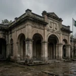 An old Pakistani district courthouse with a scales-of-justice relief and the Pakistani flag under a grey overcast sky, October 2026