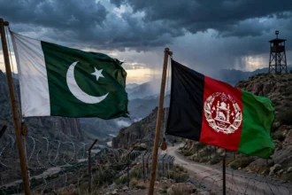 Flags of Pakistan and Afghanistan at a fenced mountain border crossing at dusk as Deputy PM Ishaq Dar warns the Afghan Taliban regime of consequences over terrorism inaction, October 2026
