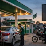 An editorial illustration of a petrol pump fuel station in Pakistan at dusk, with attendants refuelling a car and a motorcycle and a blank fuel-price display board, October 2026